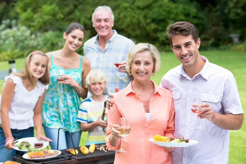 Portrait of happy multi-generation family enjoying barbecue and wine