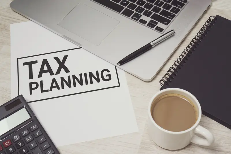 laptop, calculator, book, cup of tea and a paper which says tax planning